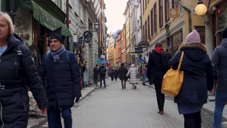 La-Gente-Camina-Por-Una-Calle-Estrecha-En-El-Casco-Antiguo-De-La-Ciudad-De-Estocolmo,-Edificios-Coloridos