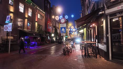 Nighttime-Amsterdam-street-scene-with-people,-restaurants-and-city-lights