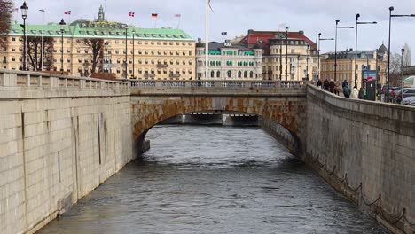 Stone-bridge-over-canal-and-downtown-buildings-in-Stockholm,-static-view