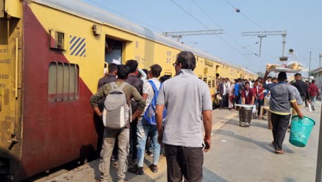 The-train-is-standing-on-the-platform,-passengers-are-boarding-the-train,-and-food-vendors-are-selling-food-at-the-railway-station-platform