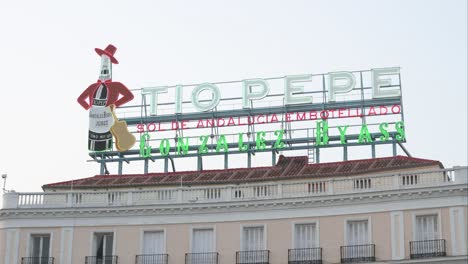 El-Emblemático-Cartel-Publicitario-De-Neón-De-Tío-Pepe,-Situado-En-La-Puerta-Del-Sol-De-Madrid,-Representa-La-Conocida-Marca-De-Vino-Seco-De-Jerez.