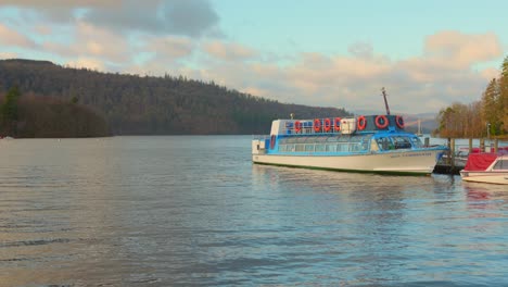 Tour-boat-and-motorboat-moored-by-jetty-on-lake-Windermere-at-dusk