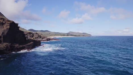 Drohnenaufnahmen-Entlang-Der-Küste-Von-Oahu-Auf-Den-Hawaii-Inseln,-Die-über-Den-Blauen-Pazifik-Gleiten,-Während-Die-Weißen-Schaumkronen-Der-Wellen-Gegen-Die-Felsige-Küste-Krachen