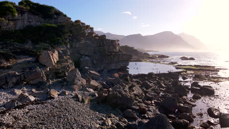 Drone-Al-Amanecer-Hacia-La-Piscina-Marina-Hermanus-Con-Gente-Haciendo-Inmersión-En-Agua-Fría