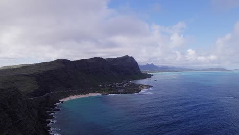 aerial-footage-of-calm-blue-Pacific-ocean-waters-against-the-volcanic-formations-in-the-Hawaiian-island-of-Oahu-with-blue-sky-and-white-puffy-clouds