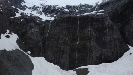 Captivating-ascent-over-glacier-valley-and-above-snow-covered-mountain-in-Fiordland,-New-Zealand,-South-Island