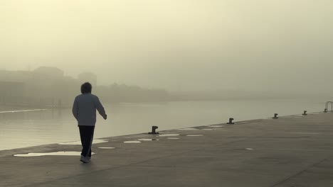Static-view-of-man-walks-alone-in-the-fog-on-a-pier-