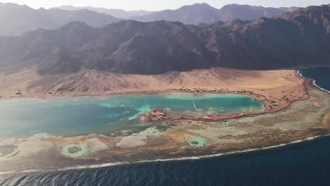 Aerial-view-captures-the-stunning-blue-lagoon-in-Dahab,-Egypt,-offering-breathtaking-scenery-of-the-surrounding-desert-landscape,-guaranteeing-visitors-an-unmatched-and-unforgettable-experience
