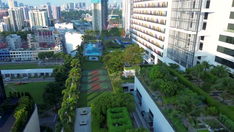 Vista-Aérea-Del-Paisaje-De-Drones-De-La-Piscina-Del-Complejo-Hotelero-En-La-Azotea-Con-Jardines,-árboles,-Horizonte-De-Fondo-De-La-Ciudad-De-CBD-En-Farrer-Park,-Singapur,-Asia,-Diseño-Arquitectónico