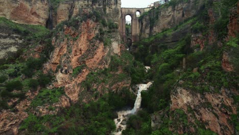 Pan-left-4k-drone-aerial-view-of-waterfall-and-Puente-Nuevo-bridge-in-Ronda,-Andalusia,-Spain