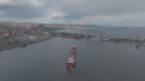 Aerial,-Cargo-Ship-Leaving-Duluth-Harbor-in-Minnesota-on-an-Overcast-Day