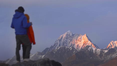 Sichuan-Yala-Snow-Mountain-with-alpenglow-as-couple-stands-to-side-out-of-focus