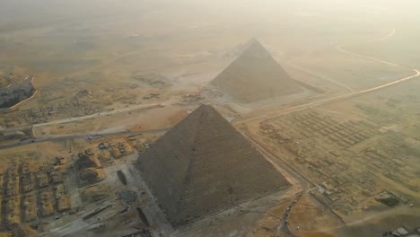 Aerial-perspective-of-the-grandeur-of-Egypt's-Great-Pyramids-of-Giza,-and-the-historic-Pyramids-Plateau,-evoking-the-enduring-marvel-of-ancient-times-and-timeless-splendor