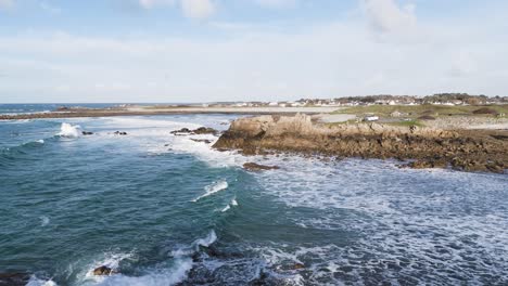 Foaming-waves-coming-ashore-on-beach-and-rocks-on-bright-sunny-day-In-Guernsey-the-Channel-Islands