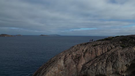 Group-of-people-on-top-of-rocky-coastal-cliffs-in-Western-Australia-during-cloudy-day