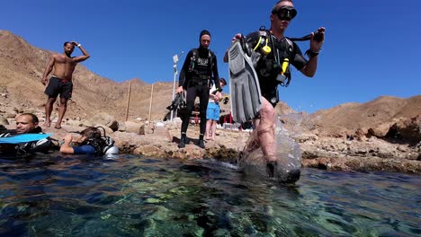 Scuba-Divers-On-Shore-Ready-To-Dive-Into-The-Red-Sea-In-Dahab,-Egypt