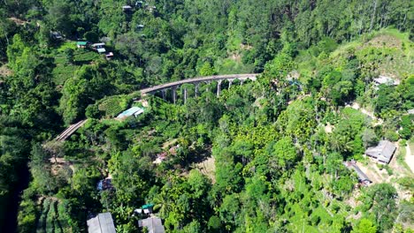 Aerial-drone-shot-of-Nine-Arch-Bridge-in-Ella-Sri-Lanka-colonial-era-train-railway-transport-line-surrounded-by-forest-faming-trees-agriculture-nature-Asia