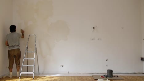 A-Man-Painting-Wall-Using-A-Limewash-Grey-Paint