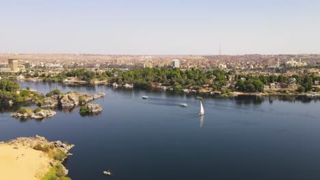 Aerial-of-the-Nile-River-adorned-with-Feluccas,-traditional-Egyptian-sailing-boats,-in-Aswan,-Egypt,-embodying-the-concept-of-timeless-maritime-heritage-and-cultural-richness