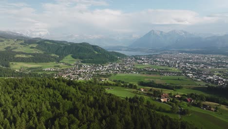 Aerial-of-a-forest-with-a-small-town-and-mountains-in-the-background