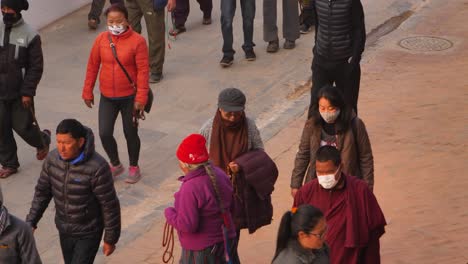 Close-shot-of-people-walking-around-the-outer-section-of-Boudhanath-Temple,-Kathmandu,-Nepal