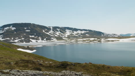 Small-lake-on-a-top-of-a-mountain-coverd-with-snow-at-summer