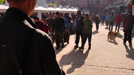 Medium-ground-level-shot-of-people-walking-around-the-outer-section-of-Boudhanath-Temple,-Kathmandu,-Nepal