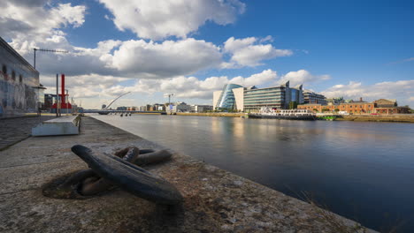 Lapso-De-Tiempo-Del-Canal-Fluvial-De-Hormigón-En-La-Ciudad-De-Dublín-Con-Un-Gran-Gancho-De-Cadena-De-Barco-De-Hierro-Durante-El-Día-Con-Nubes-En-El-Cielo-Reflejándose-En-El-Río-Liffey-En-Irlanda