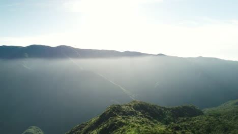 Aerial-of-Sunlight-Over-the-Jungle,-Mountains-in-the-Background