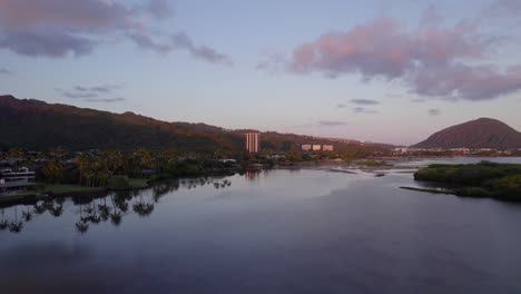 drone-footage-across-calm-water-and-sandbars-in-East-Honolulu-on-the-island-of-Oahu-in-Hawaii-with-the-alpenglow-of-the-recent-sunset-reflecting-pink-on-the-clouds-and-purple-mountain