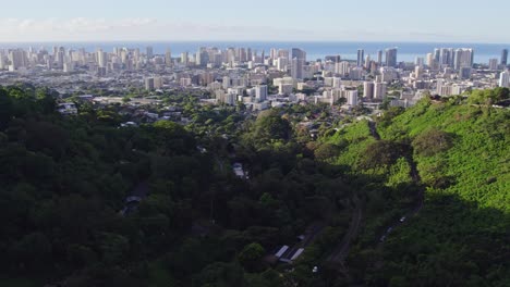 stationary-footage-of-the-city-of-Honolulu-Hawaii-on-the-island-of-Oahu-as-seen-through-a-mountain-ravine-filled-with-lush-greenery-the-ravine-is-shaded-in-early-afternoon