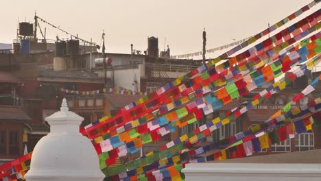 Vistas-Del-Atardecer-De-Banderas-De-Oración-Y-Edificios-Circundantes-En-El-Templo-Boudhanath,-Katmandú,-Nepal