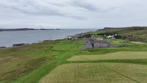 Aerial-View-of-Iona-Abbey-and-Nunnery-Ancient-Landmark-and-Homes-on-Island-Coastline,-Scotland-UK