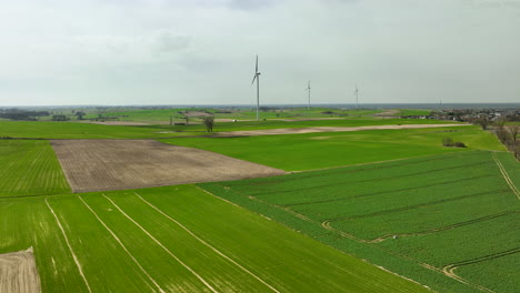 Forward-drone-shot-of-agriculture-fields-with-few-turbines-present-during-daytime