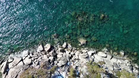 Aerial-view-of-clear-blue-Lake-Tahoe-water-and-beach-rocks-topdown