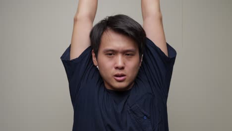 Junger-Asiatischer-Mann-Streckt-Seine-Arme-Aus-Und-Macht-Dehnübungen,-Portrait-Vorderansicht