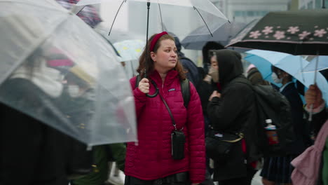 Frau-Mit-Regenschirm-Steht-Inmitten-Einer-Menschenmenge-Auf-Der-Straße-In-Shibuya