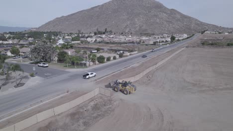 Un-Dron-Rastrea-Una-Retroexcavadora-Que-Navega-Por-Calles-Residenciales