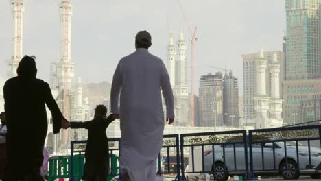 Family-strolling-and-admiring-the-sights-of-Mecca,-Saudi-Arabia,-city-skyline-as-their-backdrop