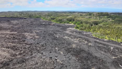 Drone-push-in-overlooks-massive-lava-fields-on-Big-Island,-Hawaii,-juxtaposing-areas-untouched-by-the-eruption-from-Leilani-Estates