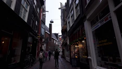 POV-tourists-walking-through-city-alley-in-Amsterdam,-Netherlands