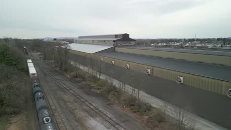 Aerial-drone-view-of-a-train-traveling-through-a-massive-industrial-facility