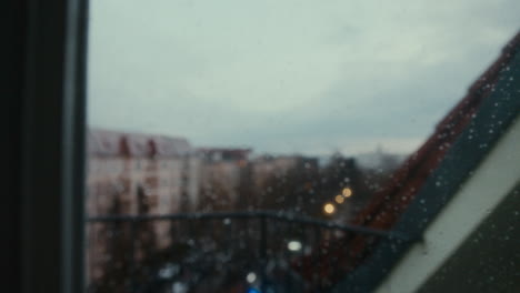 La-Ciudad-Es-Vista-Por-Alguien-Desde-Una-Ventana,-La-Cámara-Se-Reenfoca-Para-Mostrar-Las-Gotas-De-Lluvia-En-La-Ventana.