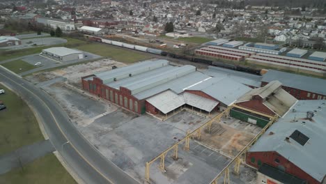 Aerial-drone-view-of-a-train-traveling-through-a-massive-industrial-facility