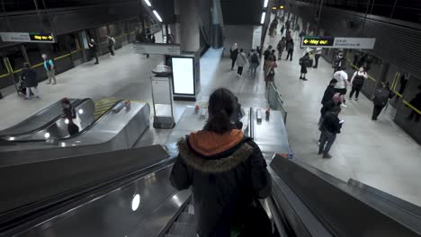 Descendiendo-Por-Escaleras-Mecánicas-En-La-Estación-De-Metro-Canary-Wharf-De-Londres,-Que-Encarna-El-Concepto-De-Tránsito-Urbano-Y-Conectividad-Metropolitana.