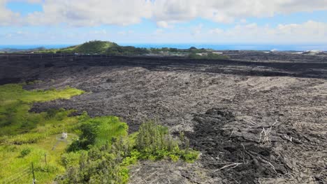 Drone-pans,-revealing-expansive-lava-fields-on-Big-Island,-Hawaii,-juxtaposed-with-unaffected-areas-from-Leilani-Estates-eruption
