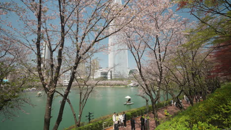 Aerial-View-Of-Seokchon-Lake-Park-With-The-Luxury-Hotel-Of-Lotte-Tower-In-The-Background-In-Seoul,-South-Korea