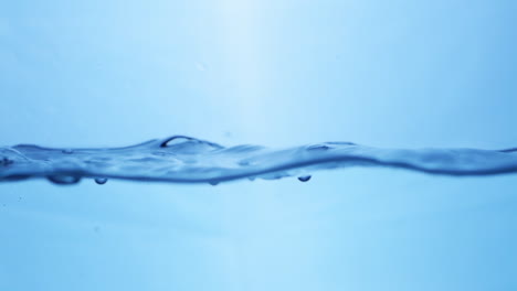 Vista-Macro-De-Dinámica-De-Fluidos-De-Gotas-De-Agua-Dulce-En-Movimiento-Sinfonía-De-La-Naturaleza-Efecto-De-Ondulación-Del-Agua-En-Cámara-Lenta-En-Tono-Azul