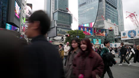 Menschen-überqueren-Die-Straße-Und-Die-Skyline-Der-Stadt-Tagsüber-In-Shibuya,-Tokio,-Japan