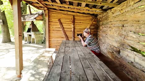 Elderly-photographer-sat-at-summer-woodland-picnic-table-taking-photos